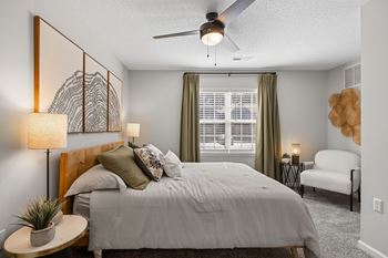 A bedroom with a bed, a ceiling fan, and a chair.
